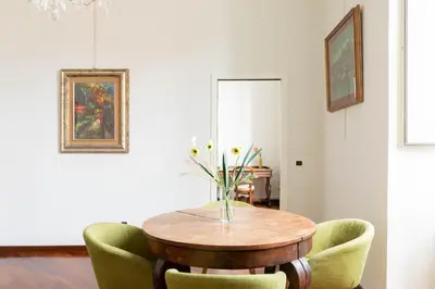 a dining room table with green chairs and a vase of flowers at Colosseum Perfect Apartment in Rome