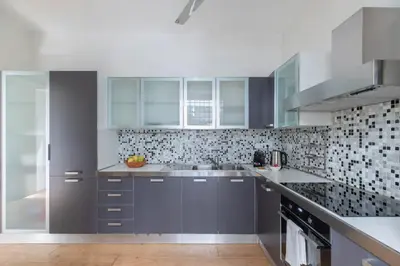 a kitchen with gray cabinets and a tile wall at iFlat Blue Cozy Loft near Saint Peter in Rome