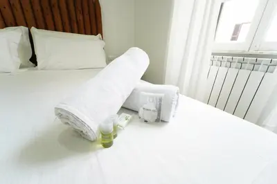 a white bed with towels and two bottles on it at Rome Vatican City Whole Apartment 3 Private Rooms in Rome