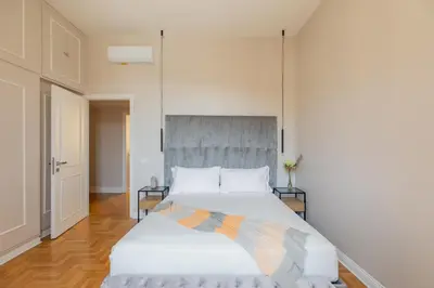 a bedroom with a large white bed with a gray headboard at Spanish Steps Caesar Suites in Rome