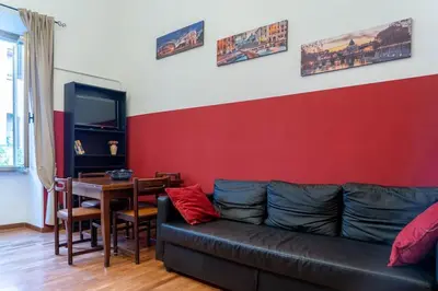 a living room with a black couch and a red wall at Trastevere - Viaggio a Roma Antica in Rome