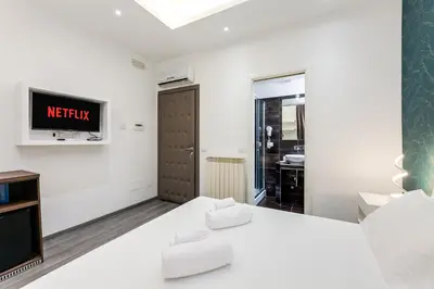 a white room with a bed and a tv at Spagna Boutique Suites in Rome
