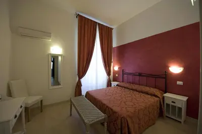 a hotel room with a bed and a chair and a window at Atlantis Inn Roma in Rome