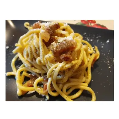 a pile of pasta sitting on a black plate at Vatican Inside House in Rome