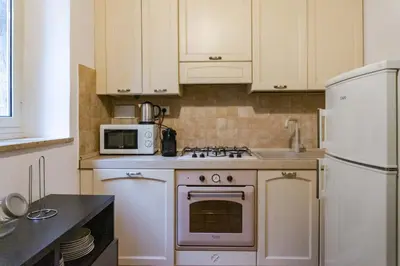 a kitchen with white cabinets and a stove and a microwave at EasyTopStay - Castel Sant'Angelo Cosy Flat in Rome