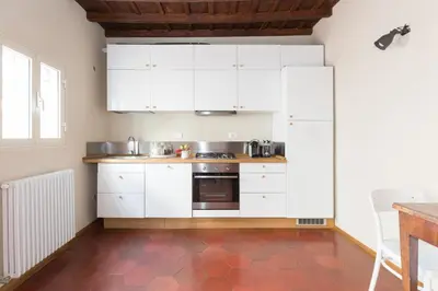 a kitchen with white cabinets and a red tile floor at Mami's Home Trastevere apt with private terrace in Rome