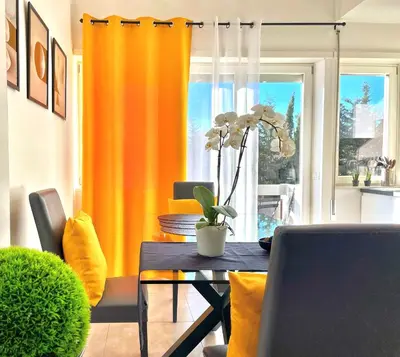 a dining room with a table and yellow curtains at L' oasi di Roma - Modern apartment with pool&parking in Rome