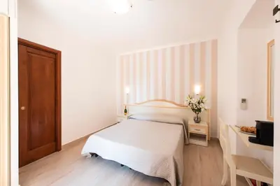 a white bedroom with a bed and a desk at La Suite di San Pietro in Rome