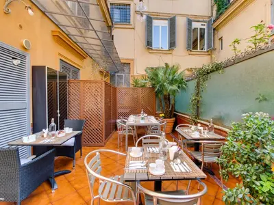 a patio with tables and chairs on a balcony at Lh Royal Suites Terrace in Rome