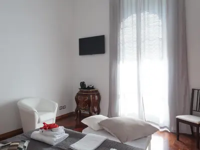 a bedroom with a bed and a chair and a window at Lh Royal Suites Terrace in Rome