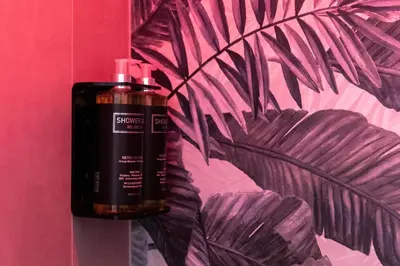 a black bottle of soap next to a pink wall at Trastevere Paper Suites in Rome