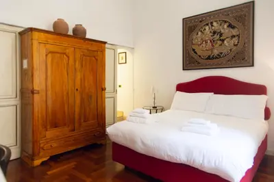 a bedroom with a large bed and a wooden cabinet at La dolce Silla - Appartamenti al Vaticano,Via Silla 91 in Rome