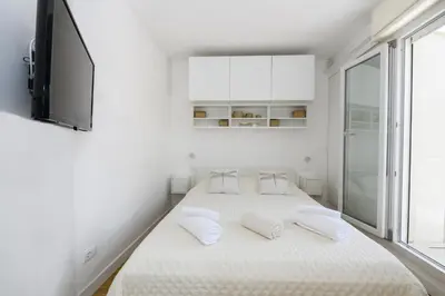 a white bedroom with two beds and a tv at Rooftop Porretta Città Giardino Check-in From 3 Pm To 10 Pm in Rome