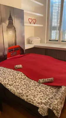 a bedroom with a bed with red sheets and a clock tower at Karol Apartment Rome in Rome