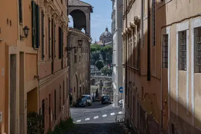 an alley between two buildings with cars driving down it at FRAM Apartment Fori Imperiali in Rome