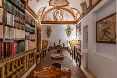 a library with a long table and bookshelves at GuestHost - Pantheon Apartment - L'angolo nascosto dei quadri in Rome