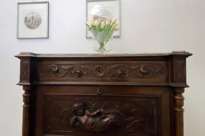 a vase of flowers on top of a wooden cabinet at Cozy Merulana in Rome