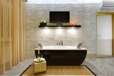 a bathroom with a bath tub with a tv on the wall at Excellence Suite in Rome