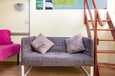 a gray couch with two pillows sitting next to a ladder at Holiday House Esedra in Rome