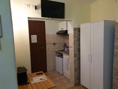 a small kitchen with a white cabinet and a television on the wall at Holiday City Centre in Rome