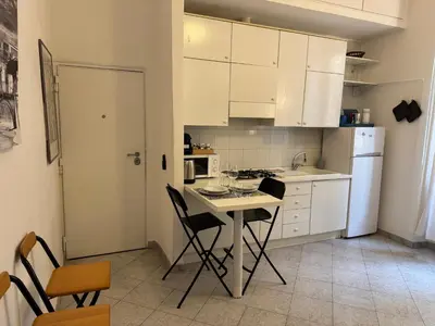 a kitchen with white cabinets and a table and chairs at Cozy apartment in Rome Trastevere in Rome