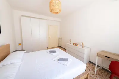 a bedroom with a white bed and a red chair at Casa Tripolitania in Rome