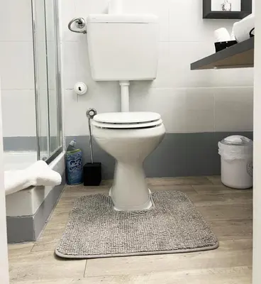 a white toilet in a bathroom with a rug at SorinaHome Vatican Studio in Rome