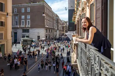 a woman standing on a balcony looking at a crowd of people at Corso Grand Suite in Rome