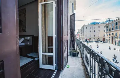 a balcony with an open door and people on a street at Corso Grand Suite in Rome