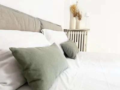 a bed with white sheets and green pillows at Appartamento a due passi da San Pietro, Vaticano in Rome