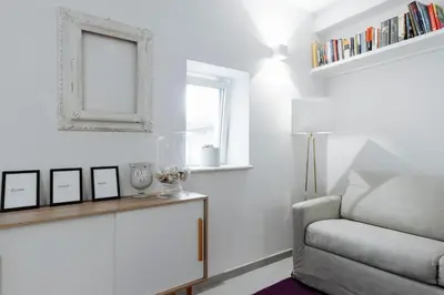 a white living room with a chair and a mirror at Pantheon Experience Suite in Rome