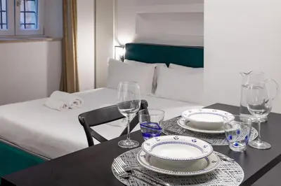 a table with two plates and glasses and a bed at Casa Annamaria al Pantheon in Rome