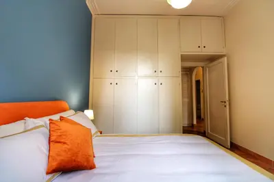 a bedroom with a bed with white cabinets and an orange pillow at Charming Vatican LargeApt by YH in Rome