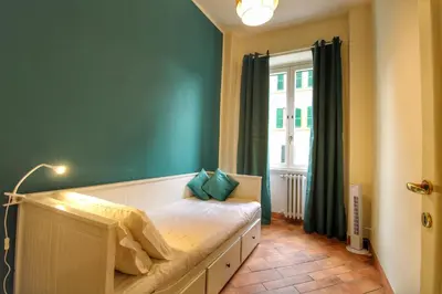 a bedroom with a bed with a green wall and a window at Charming Vatican LargeApt by YH in Rome