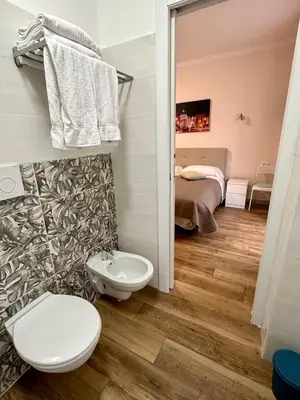 a bathroom with a toilet and a bed in a room at GOLDEN ROOMS Cipro in Rome