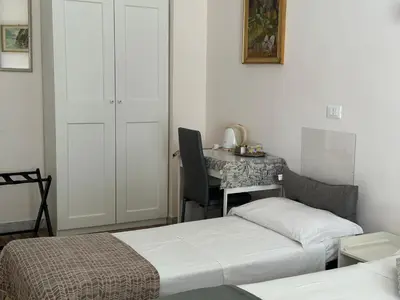 a bedroom with two beds and a table with a chair at GOLDEN ROOMS Cipro in Rome