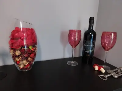 a bottle of wine and a vase of flowers and two glasses at j u b i l e h o u s e R o m e in Rome