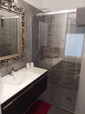 a bathroom with a sink and a shower with a mirror at j u b i l e h o u s e R o m e in Rome