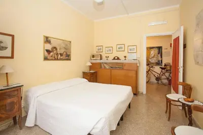 a bedroom with a white bed and a kitchen at Claudia B&B in Rome