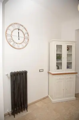 a clock on a wall next to a cabinet and a radiator at Casa vacanza Colosseo 2 in Rome