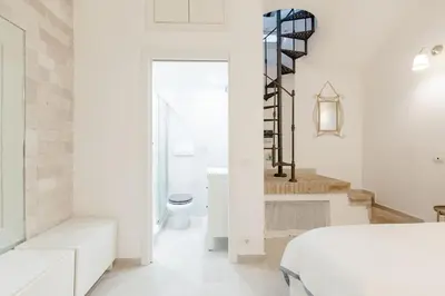 a white bedroom with a bed and a bathroom at Trastevere's Nest in Rome