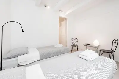 two beds in a white room with a table and chairs at Charming patio house in San Lorenzo in Rome