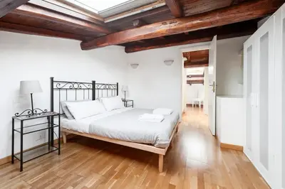 a white bedroom with a bed and a wooden floor at Charming patio house in San Lorenzo in Rome