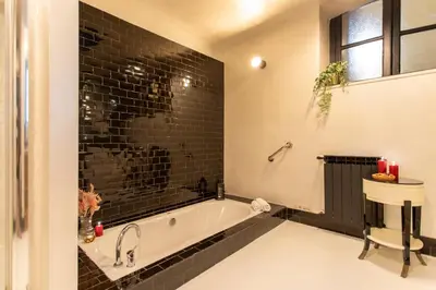 a bathroom with a tub and a black tile wall at Cloe Suite - A due passi da Villa Borghese in Rome