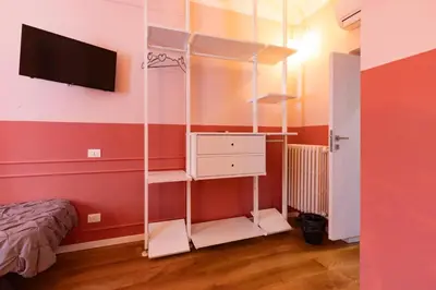a room with a bed and a tv and a shelf at Rdr Tortona Rooms in Rome