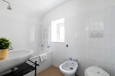 a white bathroom with a sink and a toilet at Rooftop Colosseum in Rome