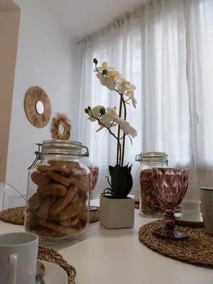 a table with a jar of cookies and a vase of flowers at Noh collection 3BDR apartment- Trastevere Area in Rome