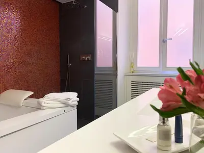 a bathroom with a white counter with a vase of flowers at ARCAsuite Tritone Luxury in Rome
