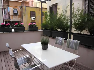 a white table and chairs on a balcony with potted plants at The Apartment at Spanish Steps in Rome