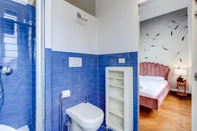 a blue tiled bathroom with a toilet and a bed at BMGA l Elegant Four-Room Apt for 8 Guests in Prati in Rome